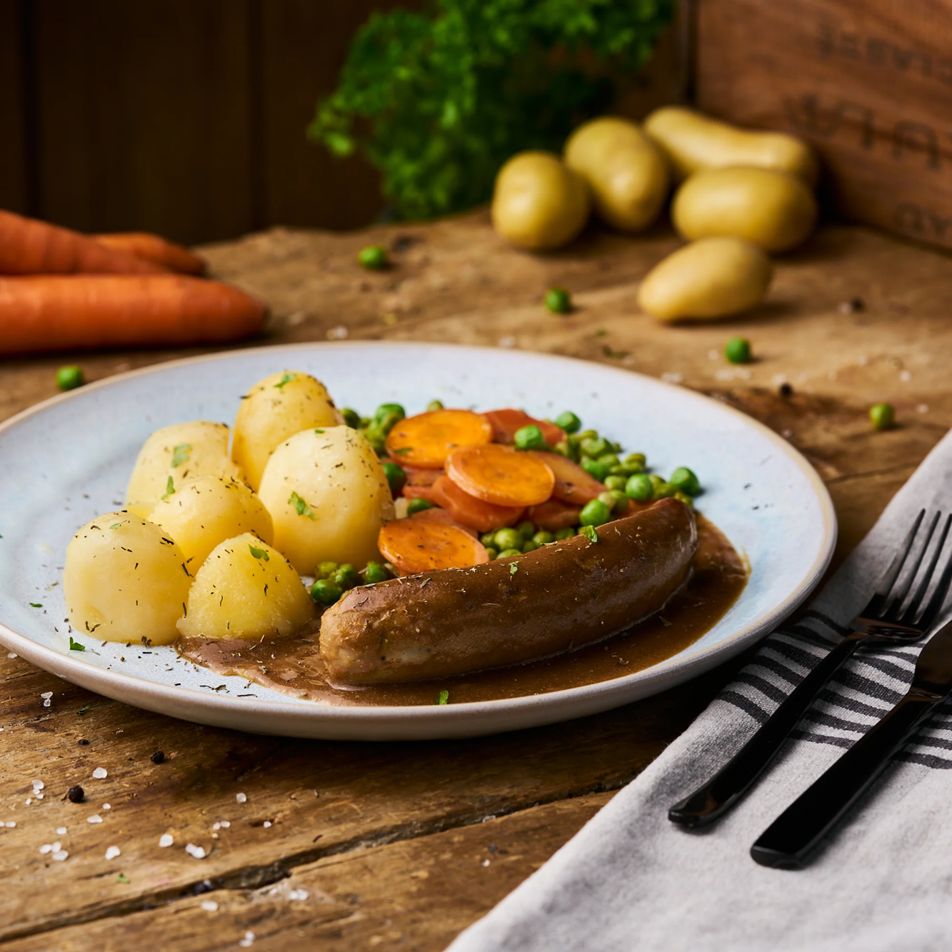 Bratwurst in Soße mit Erbsen-Karottengemüse und Butterkartoffeln